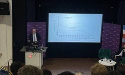 Speaker presenting slides in front of packed room